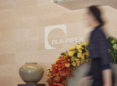 Coworker walking past wall with DLA Piper logo